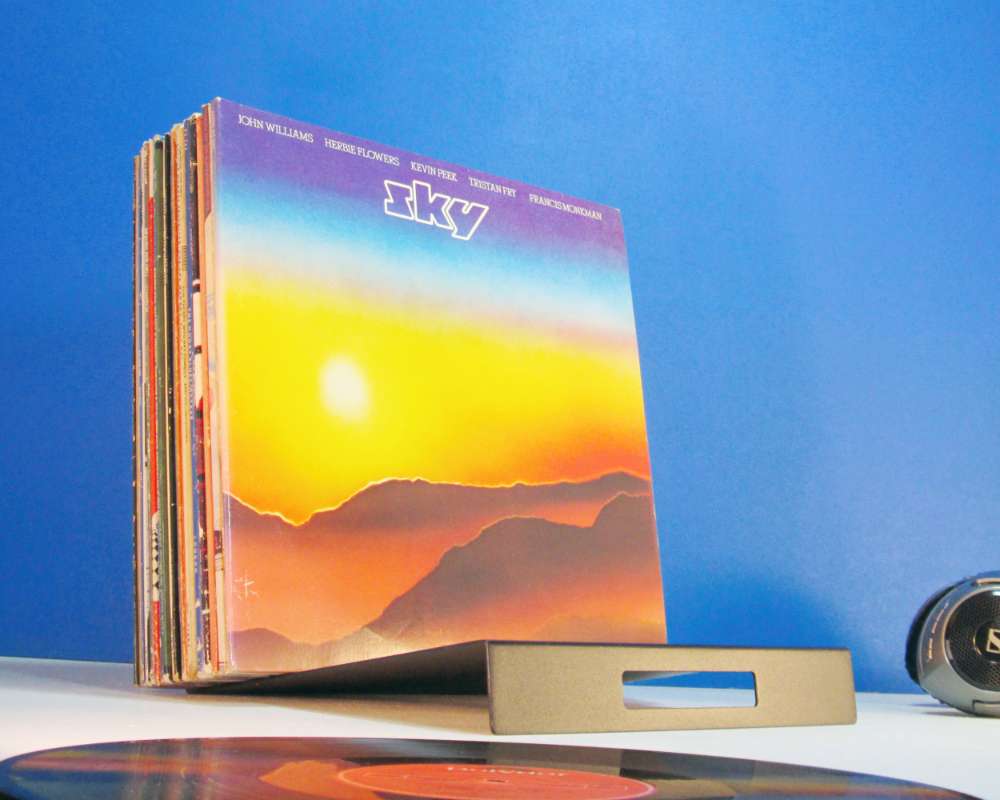a black metal sloping rack holding a collection of vinyl records